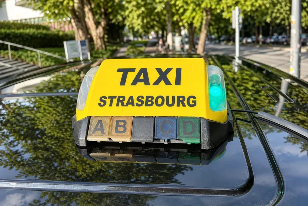 Lumineux jaune TAXI STRASBOURG sur le toit noir du van.