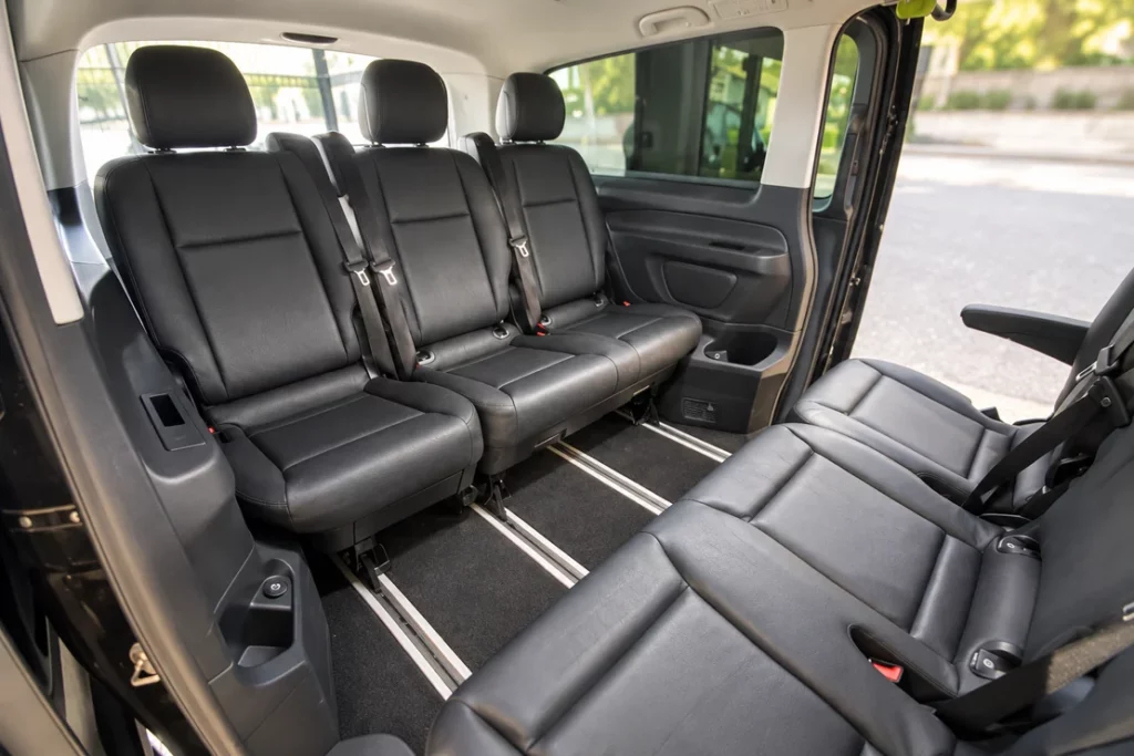 Banquettes noires face à face dans l’habitacle du van Mercedes.